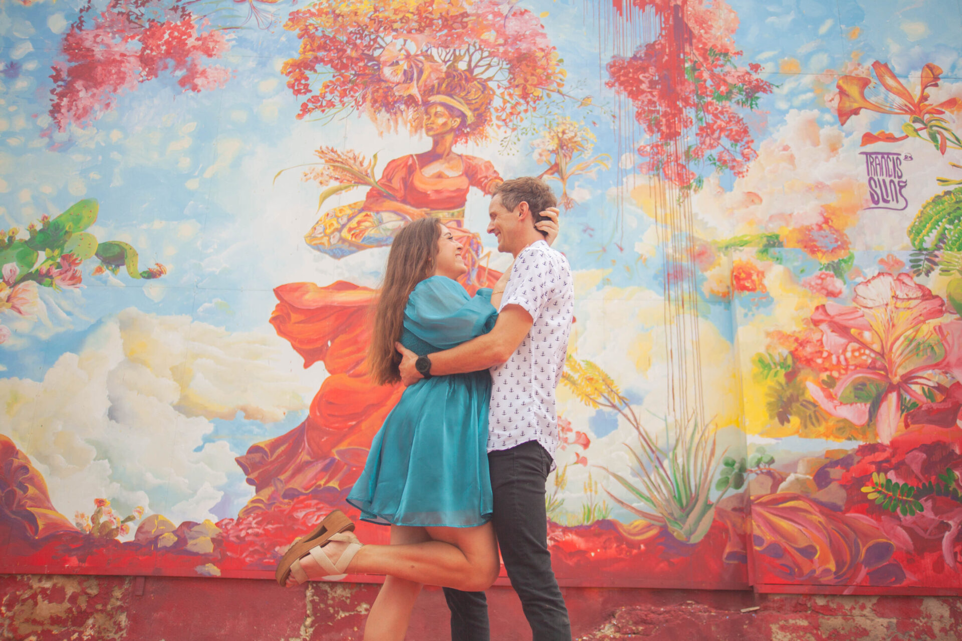 Couple embracing in front of a colorful floral street art mural in Willemstad, Curacao