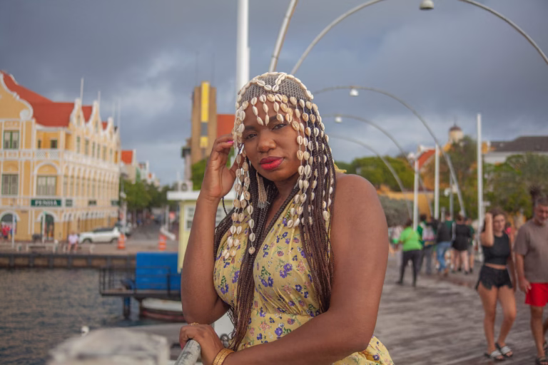 Woman posing on a pier with Willemstad's waterfront in the background