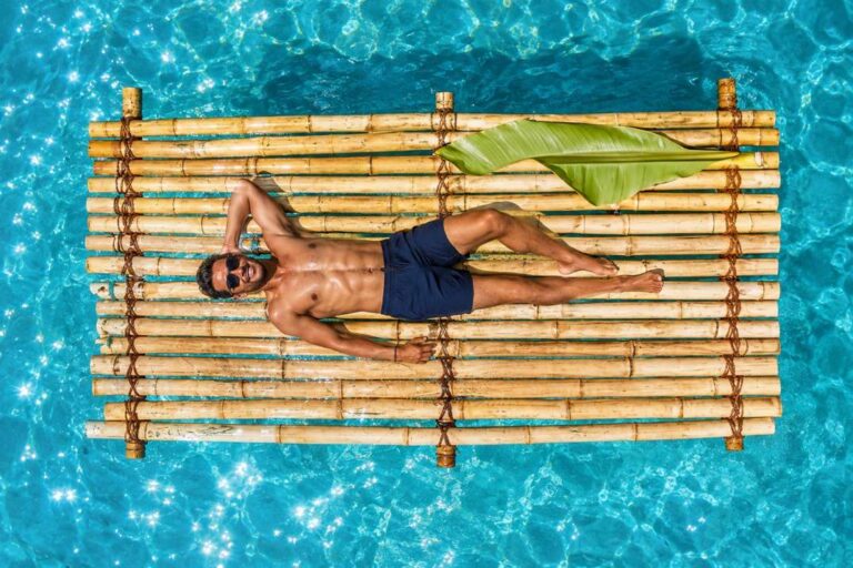 Man relaxing on a bamboo raft floating on turquoise water in Curacao