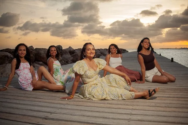 Group of women sitting together on a pier at sunset in Curacao