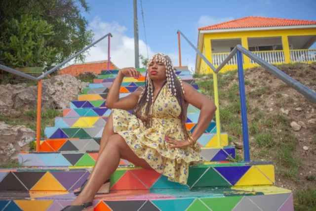 Woman sitting on a colorful painted staircase in Curacao