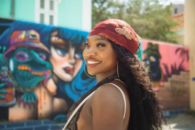 Woman smiling in front of a colorful street art mural in Curacao