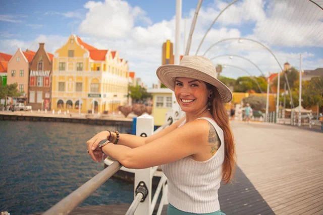 Woman posing on the Queen Emma pontoon bridge with Willemstad's colorful waterfront in the background