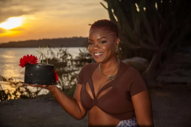 Woman smiling while holding a flowering cactus at sunset in Curacao