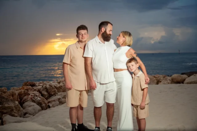 Family of three posing together at sunset by the water in Curacao