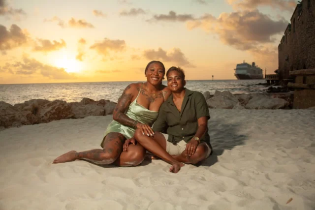 Two women sitting together on the beach with a cruise ship in the background in Curacao