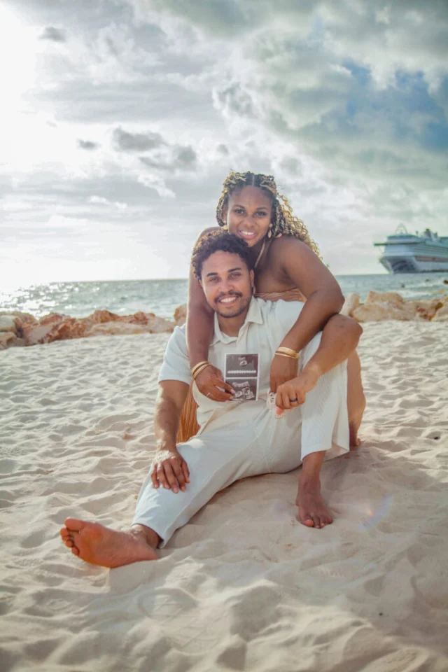 Couple sitting together on the beach with a cruise ship in the background in Curacao