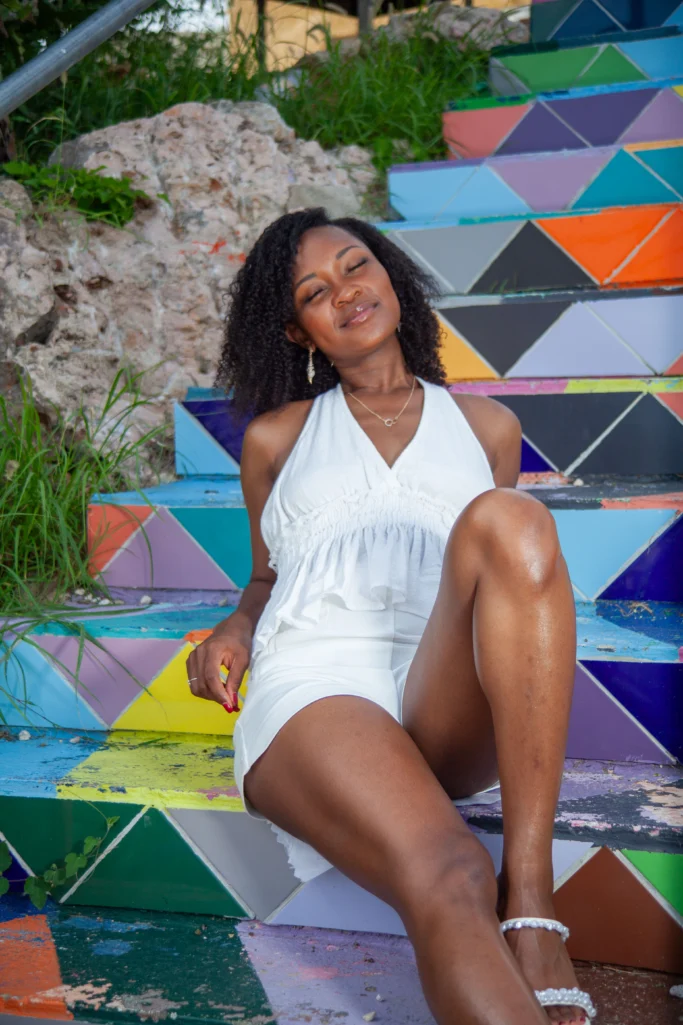 Woman in a white dress sitting on a colorful painted staircase in Curacao