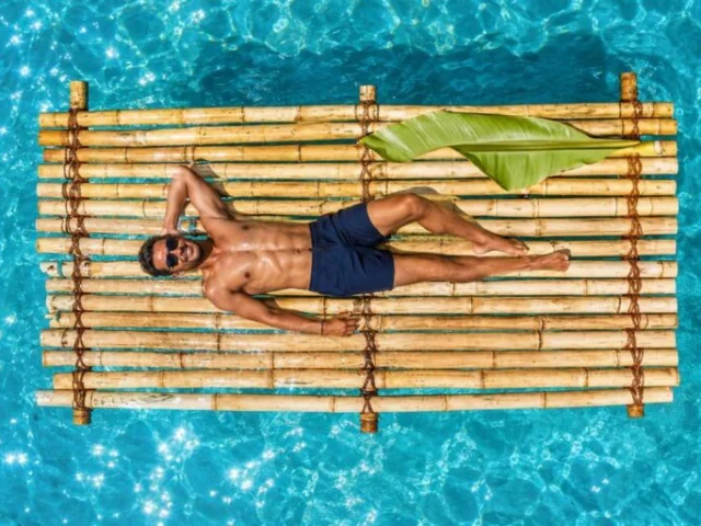 Man relaxing on a bamboo raft floating on turquoise water in Curacao