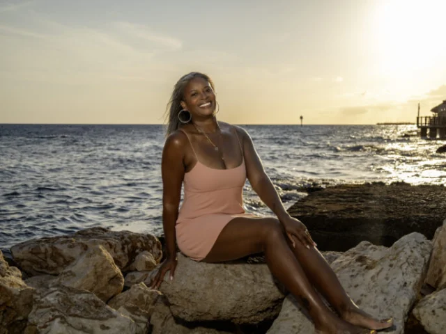 Woman posing on seaside rocks at sunset