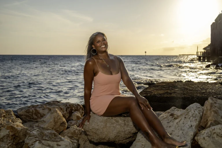 Woman posing on seaside rocks at sunset