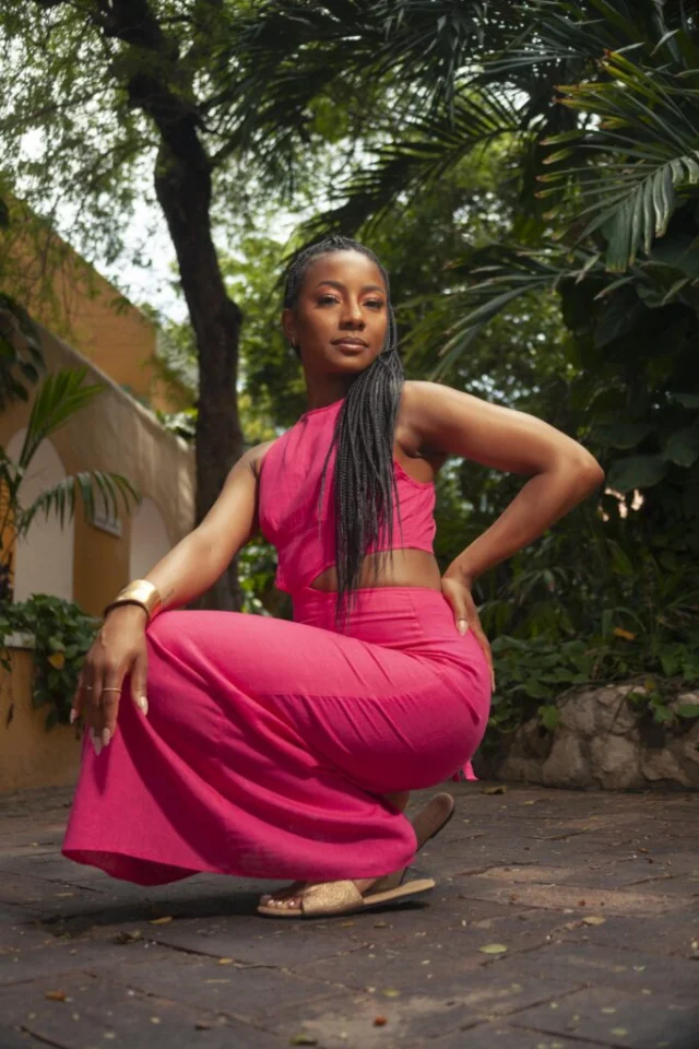 Woman in a bright pink outfit posing among tropical greenery during a Curaçao photoshoot
